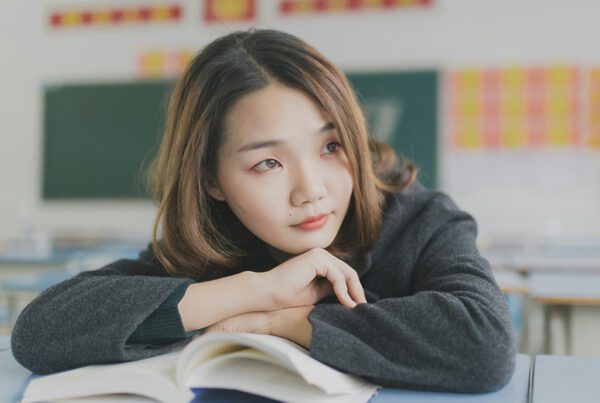 Girl looking off while reading a book in the classroom