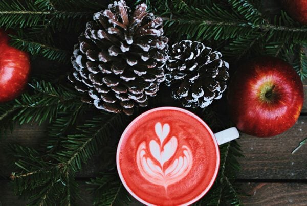 Festive hot chocolate surrounded by apples and pinecones.